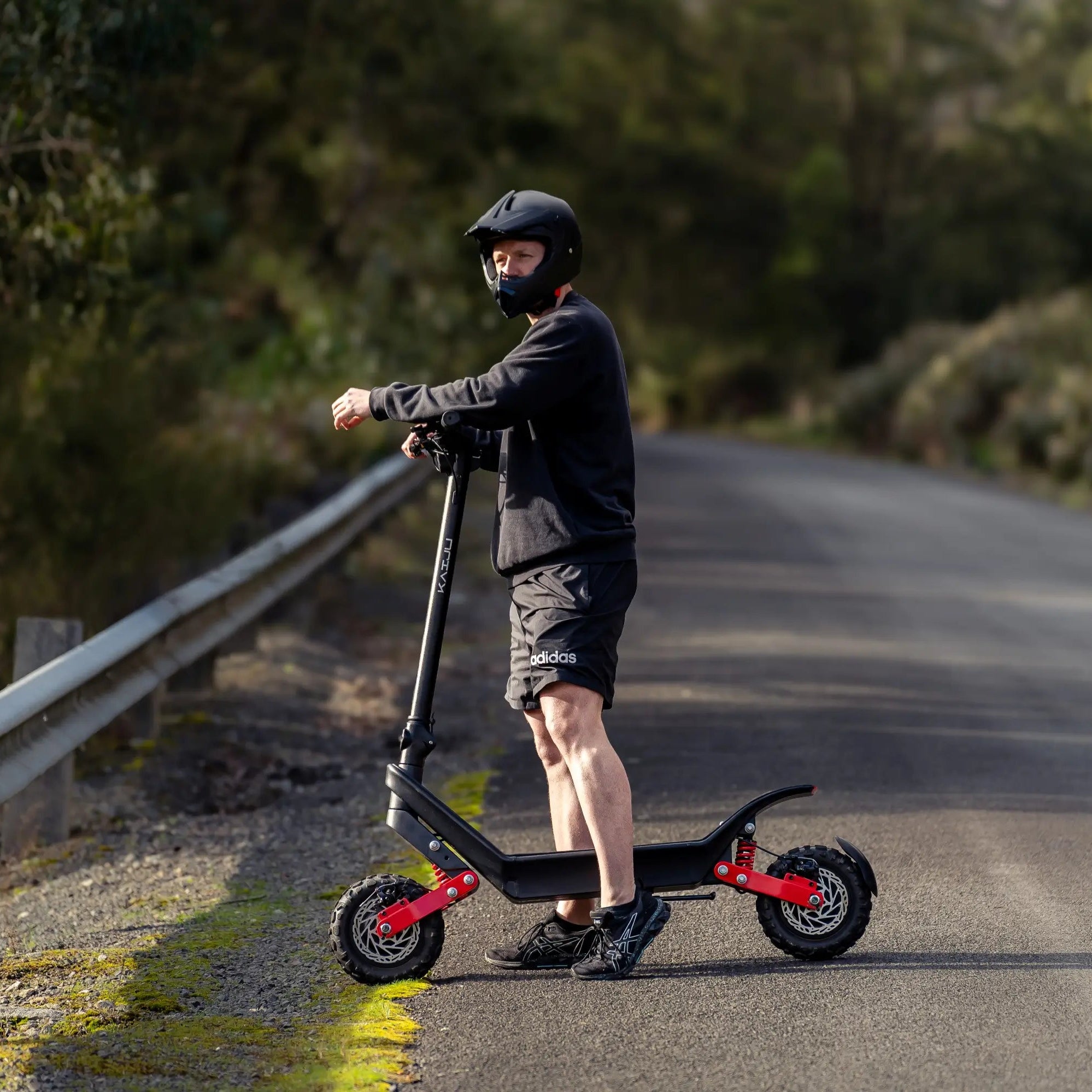 Person riding a scooter on a road with trees in the background