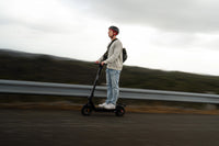 Person riding an electric scooter on a road with a blurred background