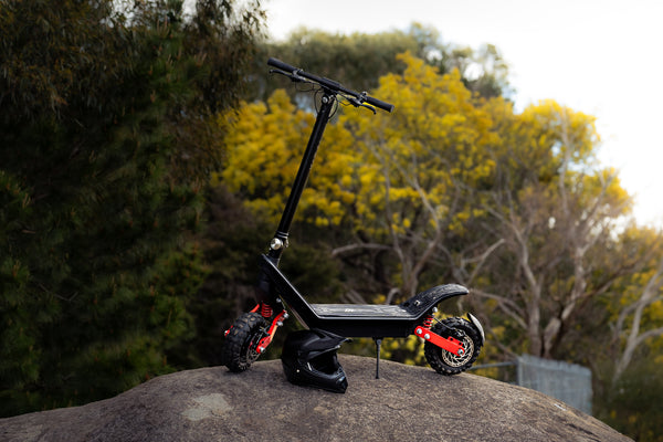 Black electric scooter on a rock with trees in the background